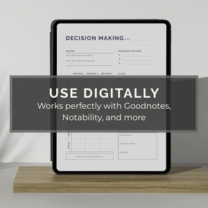 May include: A black tablet displaying a decision-making template, resting on a wooden stand. The screen shows a structured layout with sections for defining decisions and outlining options. A dark gray banner across the screen reads "USE DIGITALLY" and "Works perfectly with Goodnotes, Notability, and more."