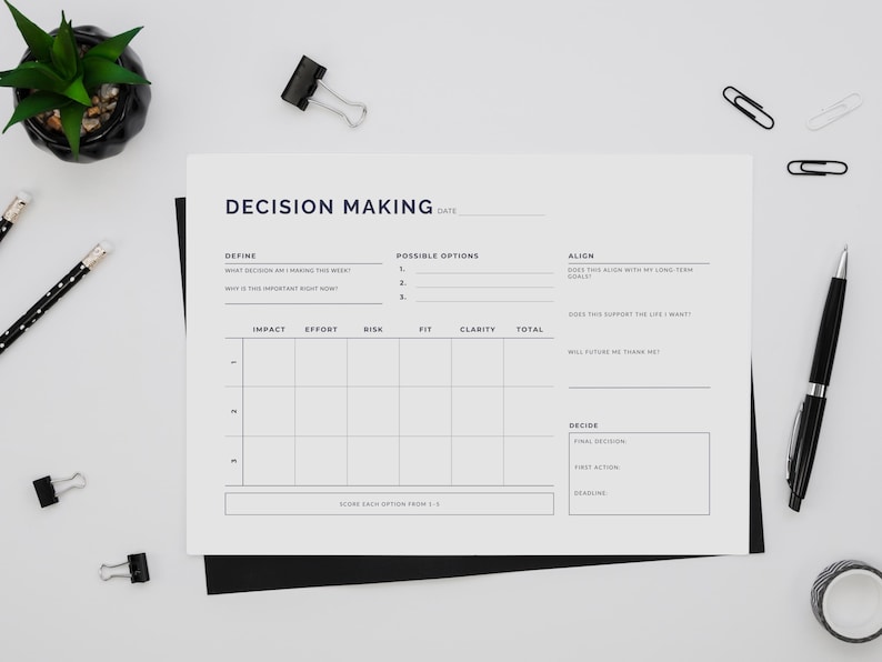 May include: A decision-making worksheet with the title "Decision Making" in a minimalist design. The worksheet includes sections for defining the decision, possible options, and aligning with goals. A black pen, pencils, and binder clips are scattered around.
