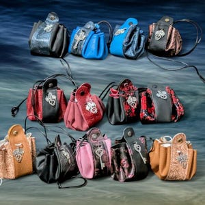 May include: A selection of small leather pouches in colours such as black, blue, red, and brown. Each pouch has unique embellishments and a drawstring closure. Some have metal accents and decorative stitching.