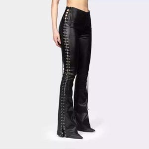 May include: Black leather trousers with a flared leg. They have a lace-up design along the side seams, with metal eyelets and laces. The trousers are a solid black colour and have a fitted silhouette.