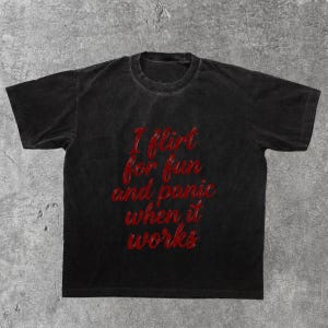 May include: Black t-shirt with the red text "I flirt for fun and panic when it works." The shirt has a vintage, washed appearance. The text is in a cursive font.