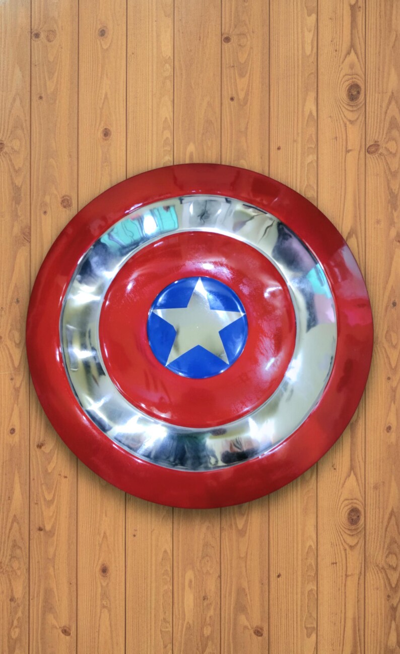 May include: A red and silver shield with a blue and white star in the center. The shield has a circular design with a red outer ring, a silver middle ring, and a red center with a blue circle and white star.