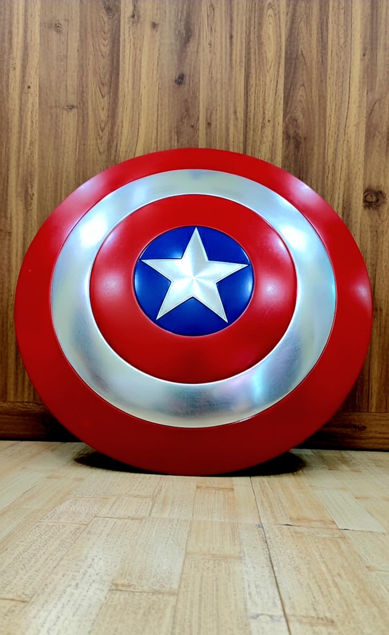 May include: A red, white, and blue shield with a star in the center. The shield has a silver ring around a blue circle with a white star. The outer ring is red.