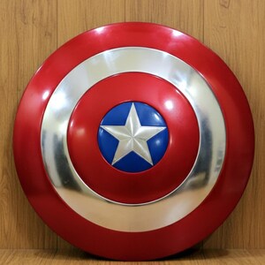 May include: A red, white, and blue shield with a star in the center. The shield has a circular design with a silver border and a blue circle in the middle, featuring a white star.