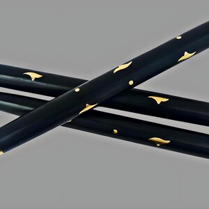 May include: Three black walking cane sections with gold-colored accents. The sections are cylindrical and feature gold leaf-like designs. The ends are capped with gold and have screw threads. The canes are arranged diagonally against a gray background.