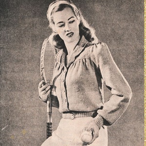 Puede incluir: Una fotografía en blanco y negro de una mujer con un cárdigan de punto y una falda blanca. Está sosteniendo una raqueta de tenis y una pelota de tenis. La foto tiene el texto "Subversive Femme" impreso en ella.