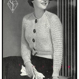 Peut inclure: Une photographie vintage en noir et blanc montrant un cardigan en tricot à manches longues de couleur claire, doté d'un motif texturé à mailles ouvertes, d'une encolure ronde et de cinq gros boutons foncés sur le devant, avec des bords côtelés.