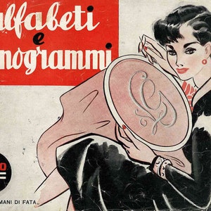 Puede incluir: Una portada de libro vintage con una mujer bordando un monograma en una tela rosa. La portada es roja y blanca con el texto "alfabeti e monogrammi" y "12= EDIZIONI "MANI DI FATA"".