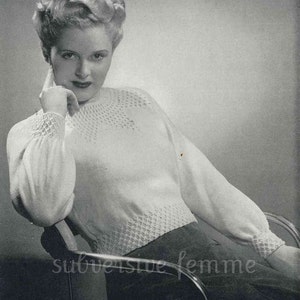 May include: A black and white photograph of a woman wearing a white knitted jumper with a lacy pattern. The jumper has long sleeves and a round neckline. The woman is sitting in a chair and has her hand on her chin. The photo is from a vintage magazine and includes the text "WISTFUL" and "See page 34".