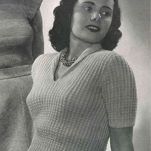 May include: A vintage knitting pattern for a women's sweater with a V-neck and short sleeves. The pattern is for a textured knit with a ribbed detail around the neckline and sleeves. The pattern is from the 1940s and features a black and white photo of a woman wearing the sweater.