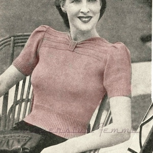 May include: A vintage knitting pattern for a pink sweater with short sleeves and a V-neck. The pattern includes instructions for creating a ribbed neckline and a decorative detail at the neckline.