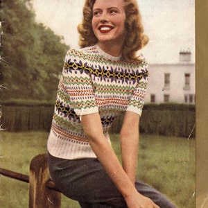 May include: A vintage knitting pattern book cover featuring a woman wearing a white, blue, and red Fair Isle sweater. The cover text reads "Patons Knitting Book No. 262" and "Fair Isles" with the price "1/-."