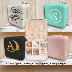 Könnte beinhalten: Vier kleine, quadratische Schmuckkästchen in verschiedenen Farben: Creme, Türkis, Schwarz und Rosa. Jedes Etui hat ein anderes Design, darunter Initialen, florale Akzente und eine Rose. Die Etuis sind geöffnet und zeigen Schmuck.