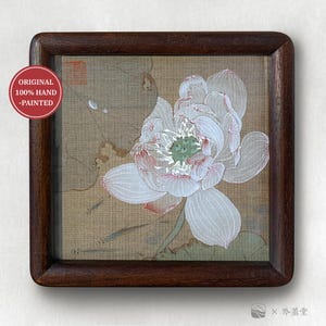 May include: A hand-painted artwork of a white lotus flower with pink accents, framed in a dark wood. The artwork is on a beige background with green leaves and the text "ORIGINAL 100% HAND -PAINTED" in a red circle.