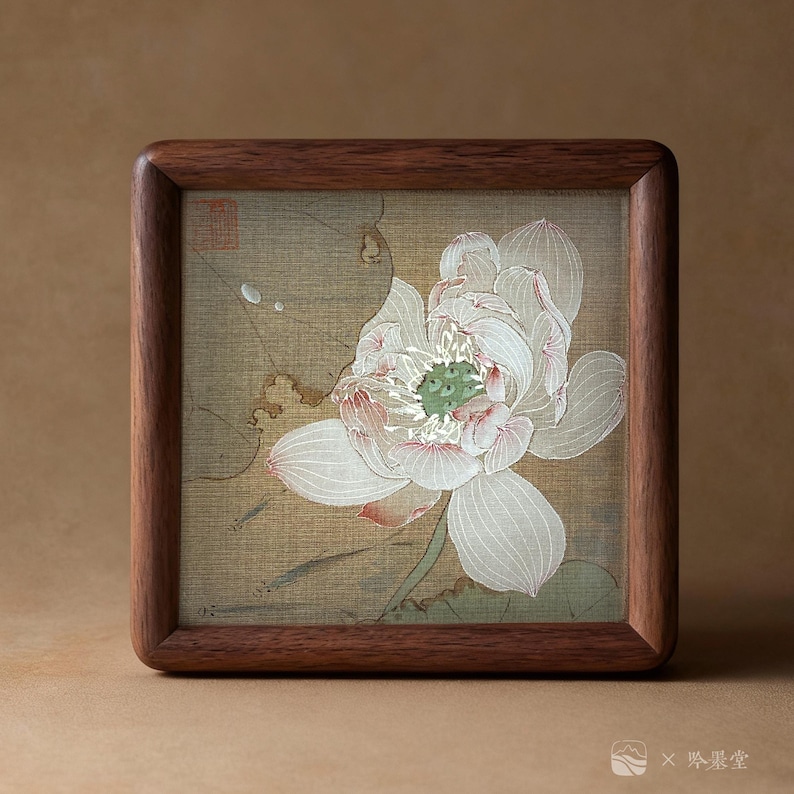 May include: A framed artwork featuring a detailed illustration of a white lotus flower with pink accents and a green center. The artwork is set against a beige background and encased in a dark brown wooden frame. The frame has rounded corners.