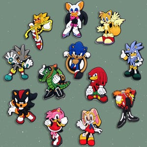 May include: Collection of colorful cartoon character charms, including Sonic the Hedgehog, Tails, Knuckles, and others. Each charm features vibrant colors and detailed designs, perfect for fans of the video game series.