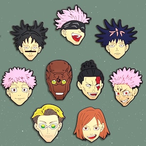 May include: A collection of cartoon character face charms in various colors. The faces have different hairstyles and expressions, including pink, black, and blue hair. Some characters have accessories like glasses or a blindfold.