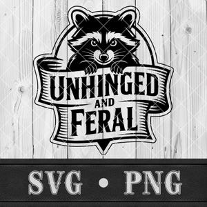 May include: Black and white graphic of a raccoon peeking over a banner. The banner reads "UNHINGED and FERAL" in bold, stylized lettering. Below the banner are the letters "SVG" and "PNG". The background is a light wood grain.