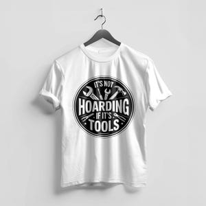 May include: White t-shirt with a black and white graphic. The graphic features tools like a wrench, hammer, and pliers inside a circular design. The text reads "IT'S NOT HOARDING IF IT'S TOOLS."