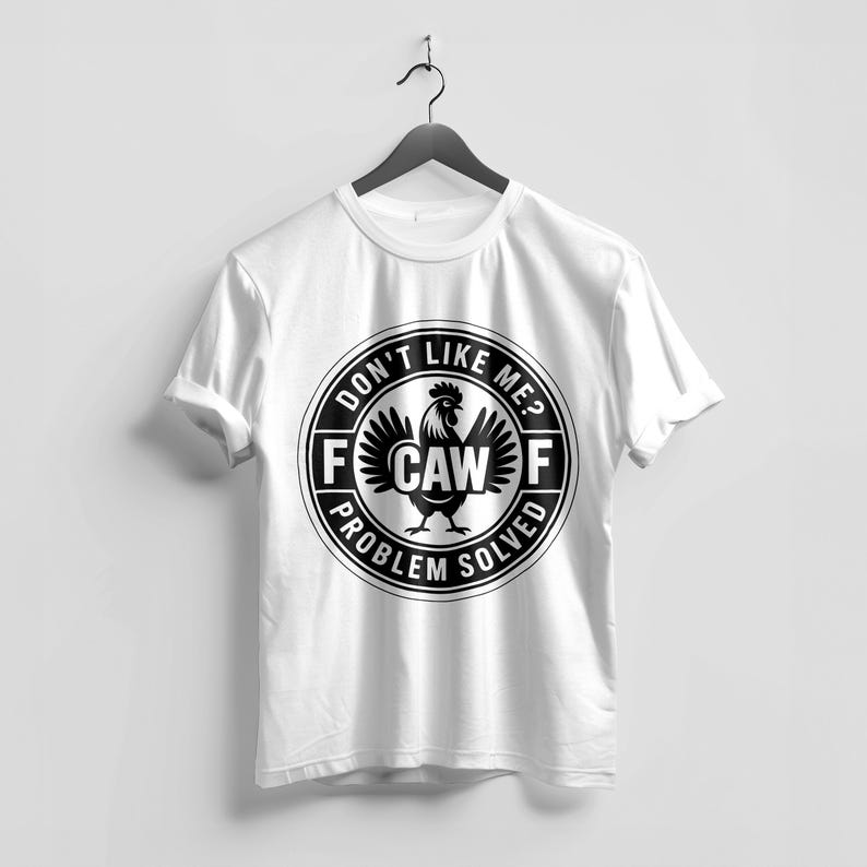 May include: White t-shirt with a black and white graphic. The graphic features a rooster and the text "DON'T LIKE ME? PROBLEM SOLVED" in a circular design. The shirt is hanging on a black hanger.
