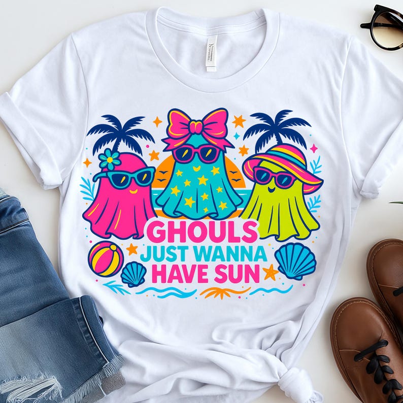 May include: White t-shirt featuring a colorful graphic of three cartoon ghosts wearing sunglasses and beach attire. The text "GHOULS JUST WANNA HAVE SUN" is below the ghosts. A fun, summery design.