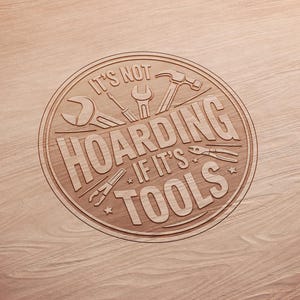 May include: A circular wooden sign with the phrase "IT'S NOT HOARDING IF IT'S TOOLS" engraved in a light brown color. The sign features illustrations of various tools, including a wrench, screwdriver, hammer, and pliers.