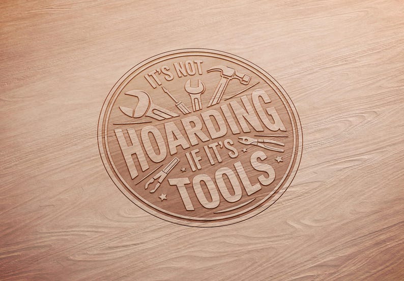 May include: A circular wooden sign with the phrase "IT'S NOT HOARDING IF IT'S TOOLS" engraved in a light brown color. The sign features illustrations of various tools, including a wrench, screwdriver, hammer, and pliers.