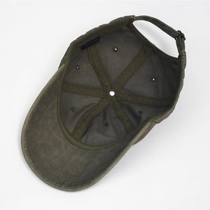 Puede incluir: Gorra de b&eacute;isbol verde oliva con visera curva y correa ajustable. El interior presenta un forro verde oscuro y una corona estructurada. La gorra tiene seis ojales de ventilaci&oacute;n y una correa de tela para ajustar la talla.
