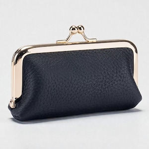 以下が含まれることがあります： テクスチャード加工された革の外装を備えた、長方形の濃いネイビーブルーの小銭入れ。 金色の金属フレームと留め金が付いています。 留め金はダブルボールのデザインです。 小銭入れは閉じています。