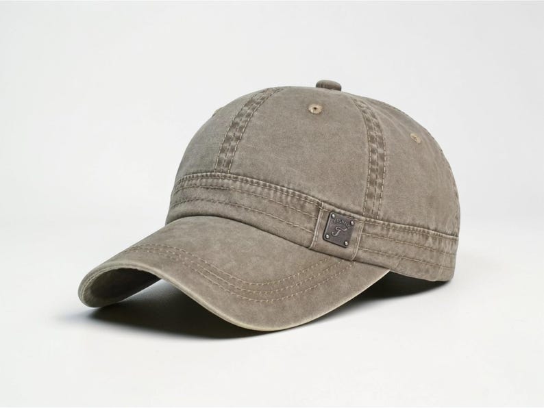 Puede incluir: Gorra de b&eacute;isbol verde oliva desgastada con visera curva. La gorra presenta un peque&ntilde;o emblema cuadrado en el lateral y detalles de costura visibles. El sombrero est&aacute; hecho de tela duradera y tiene un aspecto ligeramente descolorido.