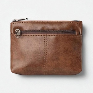 Puede incluir: Un monedero de cuero marrón con dos compartimentos con cremallera. El monedero es rectangular con una costura vertical cosida en el centro. Las cremalleras son de color plateado.