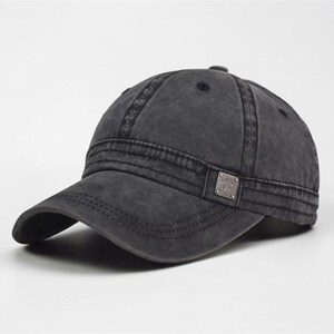 Puede incluir: Gorra de b&eacute;isbol gris carb&oacute;n con visera curva. La gorra tiene un aspecto desgastado y vintage con costuras visibles y un peque&ntilde;o emblema met&aacute;lico en el lateral. Un estilo cl&aacute;sico, adecuado para uso informal.