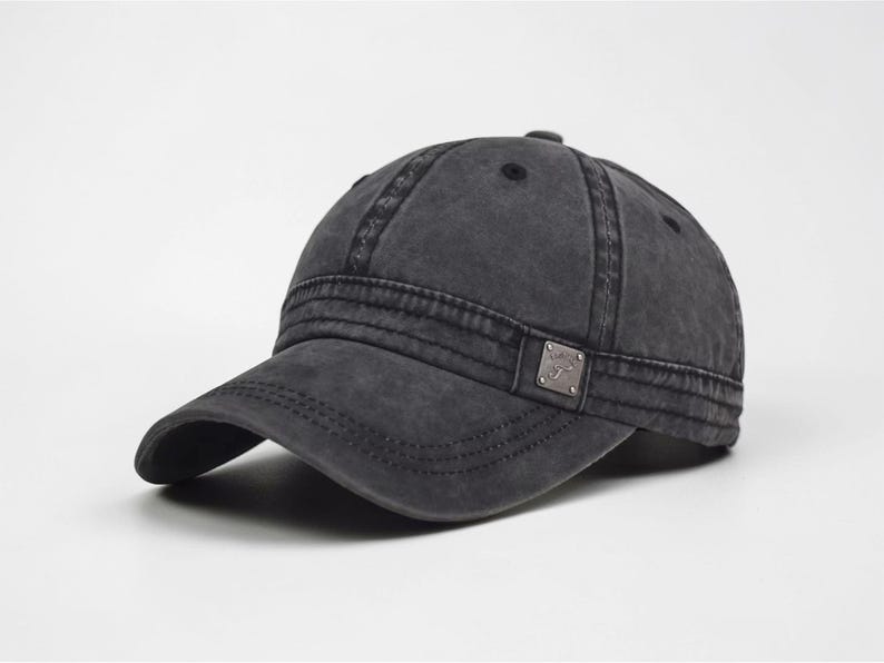 Puede incluir: Gorra de b&eacute;isbol gris carb&oacute;n con visera curva. La gorra tiene un aspecto desgastado y vintage con costuras visibles y un peque&ntilde;o emblema met&aacute;lico en el lateral. Un estilo cl&aacute;sico, adecuado para uso informal.