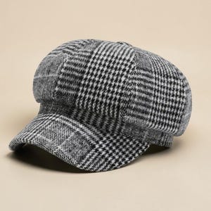 May include: A black and white plaid newsboy cap. The cap features a rounded crown and a small, stiff brim. The fabric has a classic houndstooth pattern in shades of black, white, and gray. The cap is a stylish accessory.