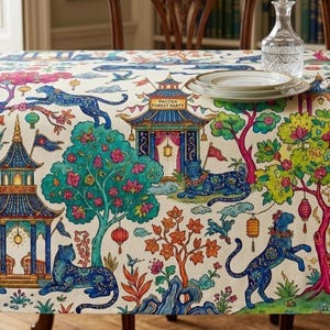 Könnte beinhalten: Eine cremefarbene Tischdecke mit einem lebendigen, sich wiederholenden Muster aus blauen Leoparden, verzierten Pagoden und bunten Bäumen. Das Design zeigt hängende Laternen, fliegende Kraniche und den Text "PAGODA FOREST PARTY".