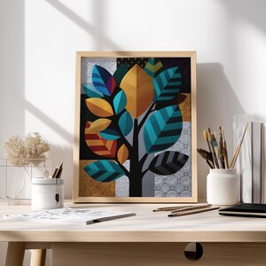 Può includere: Una stampa artistica incorniciata raffigurante un albero stilizzato con foglie colorate nei toni del verde acqua, oro, arancione e blu. L'opera d'arte è ambientata su uno sfondo patchwork. La stampa è esposta su una scrivania di legno con materiali artistici.