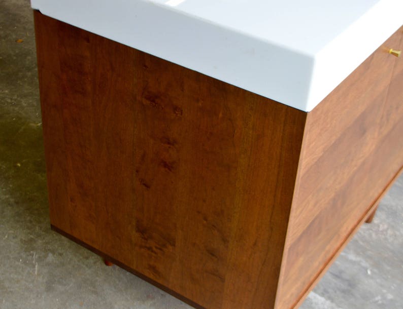 May include: A wooden cabinet with a white countertop. The cabinet has a light brown wood grain finish.
