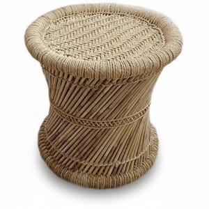 May include: A handcrafted, natural-toned woven stool. The round top and base are connected by a flared, woven body. The stool is made of natural fibers and has a sturdy, decorative design. The stool is approximately 18 inches tall.
