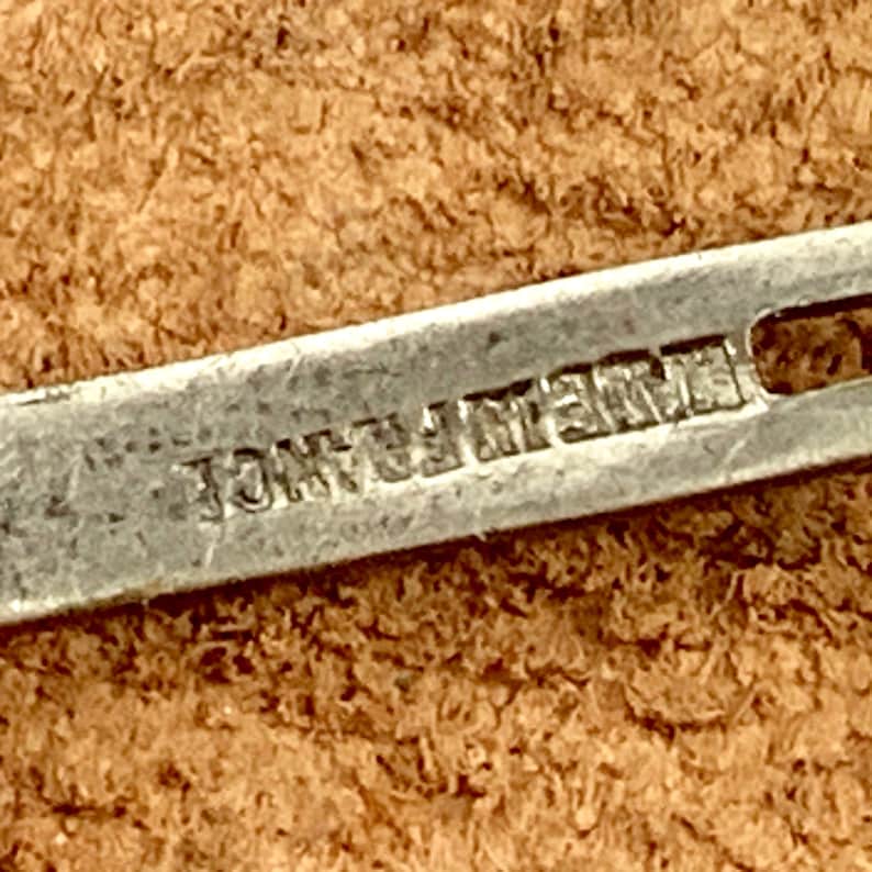 May include: Close-up of a silver metal object with the text "JONATHAN" engraved on it.