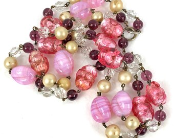 May include: A multi-strand necklace with pink, white, and burgundy glass beads. The beads are various shapes and sizes, including oval, round, and faceted.