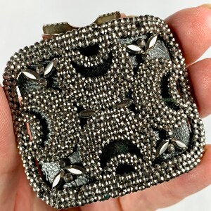 May include: A silver metal buckle with a geometric design. The buckle is covered in small, round beads.