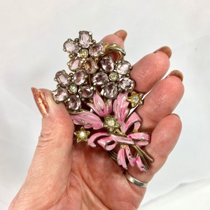 May include: A vintage pink and silver brooch featuring a bouquet of flowers with pink and clear rhinestones.