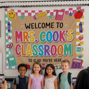 May include: A large fabric classroom banner featuring the text Welcome to Mrs. Cook's Classroom So Glad You're Here, decorated with colorful illustrations of school supplies like pencils, notebooks, scissors, and glue on a tan background.