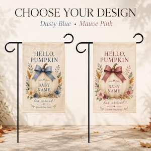 May include: Two rectangular garden flags hanging on black metal stands. Each flag features a pumpkin illustration with a bow, floral accents, and the text "HELLO, PUMPKIN", "BABY NAME", and "has arrived!" in either dusty blue or mauve pink.