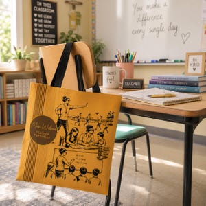May include: A mustard yellow tote bag featuring black line art illustrations of a teacher in a classroom and on a playground. The design includes a circular badge with the text Mrs. Wilson Teacher Portfolio and a chalkboard with the text Be Kind Work Hard Stay Curious.