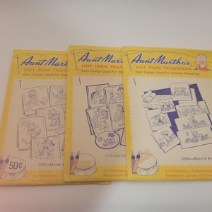 May include: Three vintage Aunt Martha's Hot Iron Transfer packets. Each packet features a yellow background with black and white illustrations of various designs for embroidery and needlepoint. The packets include images of kittens, turtles, and other motifs.