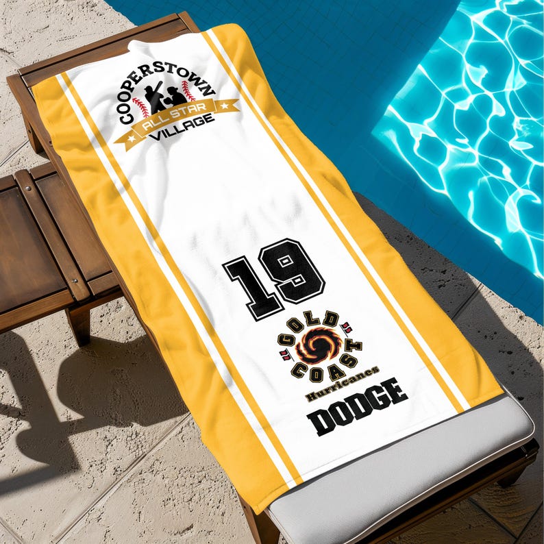 May include: A white and yellow beach towel featuring the text "Cooperstown All Star Village" and "Gold Coast Hurricanes Dodge". The towel has the number 19 in black.