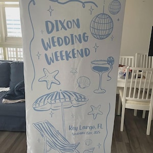 Pode incluir: Uma faixa branca com ilustra&ccedil;&otilde;es e texto em azul claro. A faixa diz "Dixon Wedding Weekend" com gr&aacute;ficos tem&aacute;ticos de praia, como um coquetel, uma bola de discoteca e uma cadeira de praia. A localiza&ccedil;&atilde;o e a data, "Key Largo, FL November 15th, 2025" tamb&eacute;m est&atilde;o inclu&iacute;das.