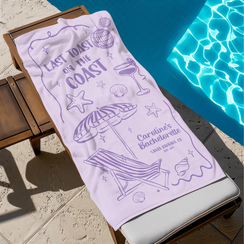 Pode incluir: Uma toalha de praia lil&aacute;s com um design de tema praiano. A toalha apresenta o texto "LAST TOAST ON THE COAST" e ilustra&ccedil;&otilde;es de uma bola de discoteca, um cocktail, estrelas do mar, conchas e um guarda-sol com uma espregui&ccedil;adeira. O texto "Caroline's Bachelorette" tamb&eacute;m &eacute; vis&iacute;vel.