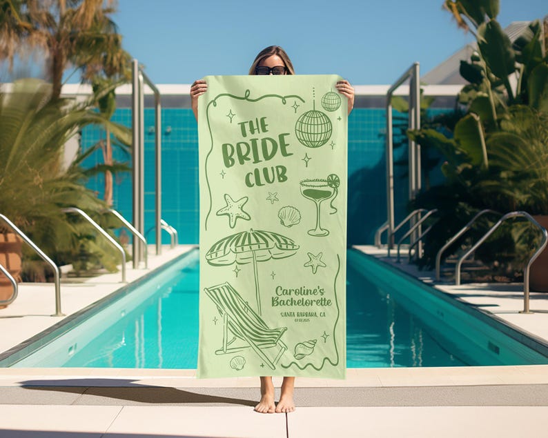 Pode incluir: Uma toalha de praia verde claro com o texto "The Bride Club" e ilustra&ccedil;&otilde;es com tema de praia. A toalha apresenta uma bola de discoteca, um cocktail, uma estrela do mar, uma concha e um guarda-sol. O texto "Caroline's Bachelorette" tamb&eacute;m &eacute; vis&iacute;vel.